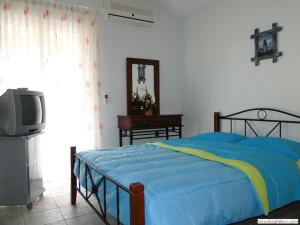 Kleo Joannas Apartments في إرميوني: غرفة نوم بسرير ازرق وتلفزيون
