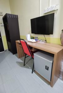 a desk with a television and a red chair at Alia Express Seri Ibai Permai in Kuala Terengganu