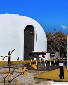 a table and chairs sitting on a deck in front of a dome house at 墾丁圓石灘 Kenting Pebble Beach in Fangshan