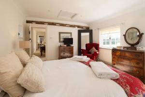 a bedroom with a large white bed and a red chair at Spilfeathers Cottage in Freyerning