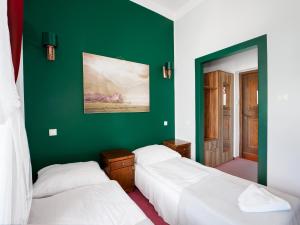 two beds in a room with a green wall at Zamek Międzylesie in Międzylesie