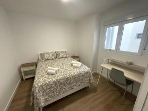 a bedroom with a bed and a desk and a window at Piso nuevo Almeria Centro in Almería