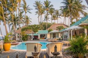 a resort pool with chairs and palm trees at Scuba Seraya Resort in Tulamben