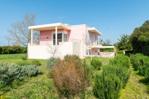 a pink house in the middle of a field at Kos Dream Beachwalk Apartment in Tigaki