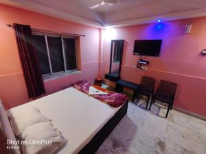 una camera con letto, scrivania e TV di Hotel Rose a kolkata