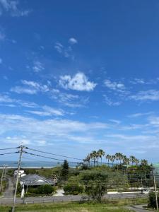 a blue sky with palm trees and a road at Hotel 4Season in Miyazaki