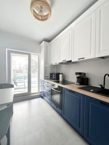 a kitchen with white cabinets and a blue island at Central, spacius apartment. in Bucharest