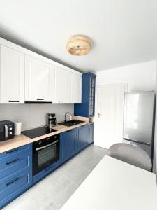 a kitchen with blue cabinets and a white refrigerator at Central, spacius apartment. in Bucharest