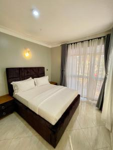 um quarto com uma cama grande e uma janela em Athena Apartments em Kampala