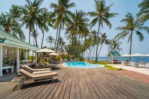 a resort with a pool and chairs and palm trees at Scuba Seraya Resort in Tulamben