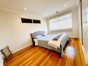 1 dormitorio con cama, ventana y suelo de madera en Townhouse Near The World’s Coolest High st in 2024 en Melbourne