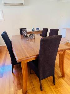 a wooden dining table with black chairs around it at Townhouse Near The World’s Coolest High st in 2024 in Melbourne