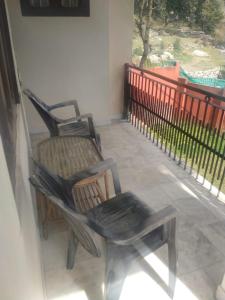 two chairs sitting on a porch next to a fence at Orchard Hotel in Dharamshala