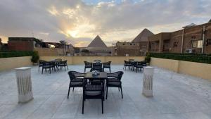 a patio with tables and chairs with pyramids in the background at The Heaven Pyramids in Cairo