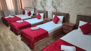 três camas num quarto com almofadas vermelhas em Ariva Center Hotel em Baku