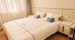 een slaapkamer met een groot wit bed met 2 kussens bij Ancient City Wall Home Apartment Xi'an in Xi'an