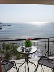 Svetlana & Michalis Oasis Hotel في أغيا مارينا ايجينا: طاولة على شرفة مطلة على الشاطئ