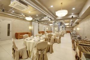 a banquet hall with white tables and chairs at Stepstones Hotels and Inn-DLF PHASE 3 GURGAON in Gurgaon