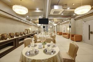 una sala da pranzo con tavoli e sedie e una cucina di Stepstones Hotels and Inn-DLF PHASE 3 GURGAON a Gurgaon