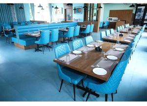 a dining room with a long table and blue chairs at Nulife Resort in Jamnagar