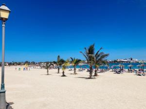 een strand met palmbomen en een lichtpaal bij Las Arenas caleta de fuste in Caleta De Fuste