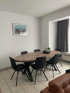 ein Esszimmer mit einem Holztisch und Stühlen in der Unterkunft Residentie Paola in Ostende