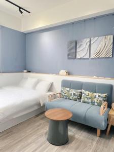 a bedroom with a bed and a blue couch and a table at N 24.8宜蘭頭城包棟民宿 in Toucheng