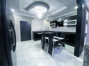 a kitchen with black cabinets and a table with black chairs at Irish Apartment in Kasoa