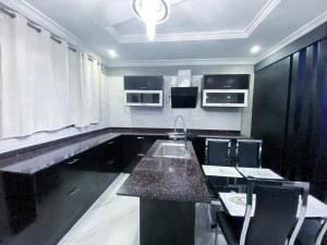 a kitchen with a sink and a table and chairs at Irish Apartment in Kasoa