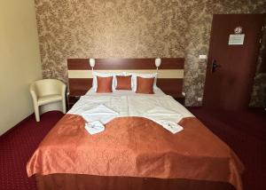 a bedroom with a large bed with red sheets and pillows at Libra Hotel in Veresegyház