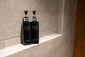 two black shampoo bottles sitting on a shelf in a bathroom at Woodstory Boutique Hotel in Bangkok