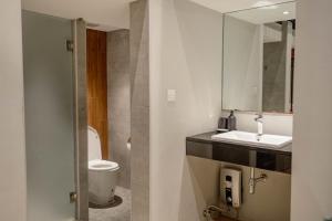 Woodstory Boutique Hotel في بانكوك: حمام مع مرحاض ومغسلة ومرآة
