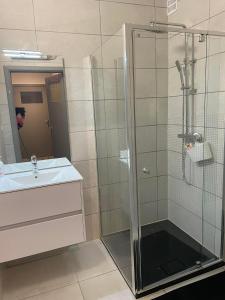 ein Bad mit einer Glasdusche und einem Waschbecken in der Unterkunft Residentie Paola in Ostende