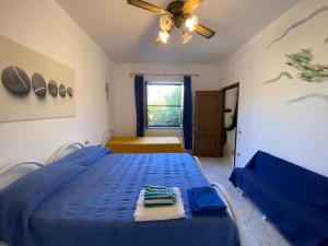 a blue bed in a room with a ceiling fan at Casa vacanza comoda con vista in Bosa