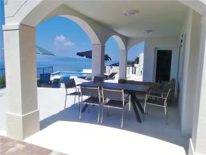a patio with a table and chairs and the ocean at Villa Glory Grande with swimmingpool and panoramic sea view in Podgora