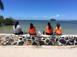 four women sitting on a wall looking at the water at LooLa Adventure Resort in Telukbakau