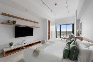 Charming and Spacious Studio في دبي: غرفة معيشة مع أريكة بيضاء وتلفزيون بشاشة مسطحة