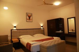 a bedroom with a large bed and a chair at Kolaahalam Mainland Resorts & Spa in Yercaud