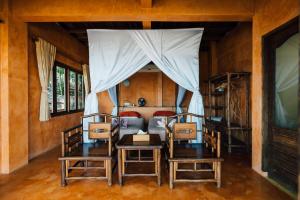 a bedroom with a canopy bed with two chairs at LooLa Adventure Resort in Telukbakau