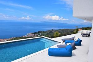 a swimming pool with chairs and a view of the ocean at Design Villa SkyBlue mit Pool und Panorama Meerblick in Podgora