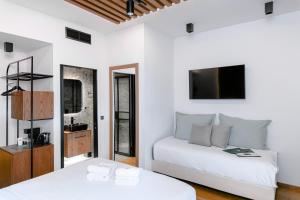 Habitación blanca con 2 camas y TV. en Snob Athens, en Atenas