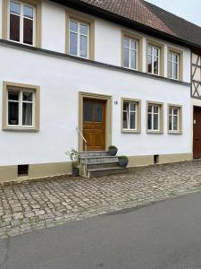 a white house with a brown door and stairs at Gästehaus LuNa in Zeil