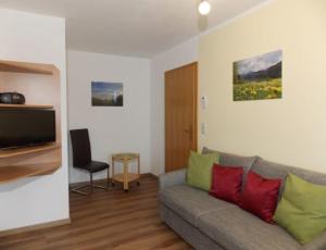Una sala de estar con un sofá y un televisor. en Ferienhof Hefele Ferienwohnung Weißensee mit KönigsCard, en Hopferau