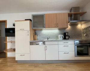a kitchen with white cabinets and stainless steel appliances at Ferienhof Hefele Ferienwohnung Hopfensee mit KönigsCard in Hopferau