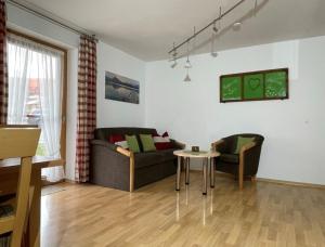 a living room with two couches and a table at Ferienhof Hefele Ferienwohnung Hopfensee mit KönigsCard in Hopferau