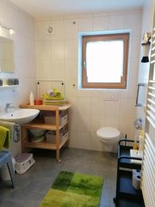 a bathroom with a sink and a toilet and a window at Ferienhof Hefele Ferienwohnung Hopfensee mit KönigsCard in Hopferau +15 photos