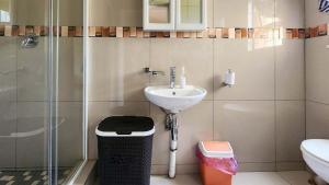 baño con lavabo, ducha y cubo de basura en Sea Park Holi-Stay - 2on1stAve, en Port Shepstone