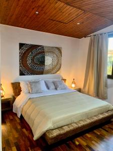 una camera da letto con un grande letto e un dipinto sul muro di "THE ATTIC" - Appartamento Esclusivo con Parcheggio Gratuito a Marano di Napoli