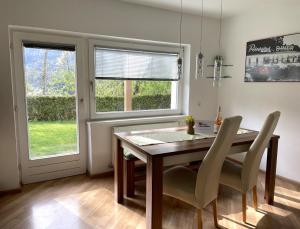 jadalnia z drewnianym stołem i dwoma oknami w obiekcie Stubai Apartment Telfes w mieście Telfes im Stubai