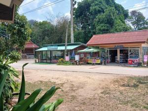 a store on the side of a dirt road with a street at Bamboo House in Khao Sok National Park